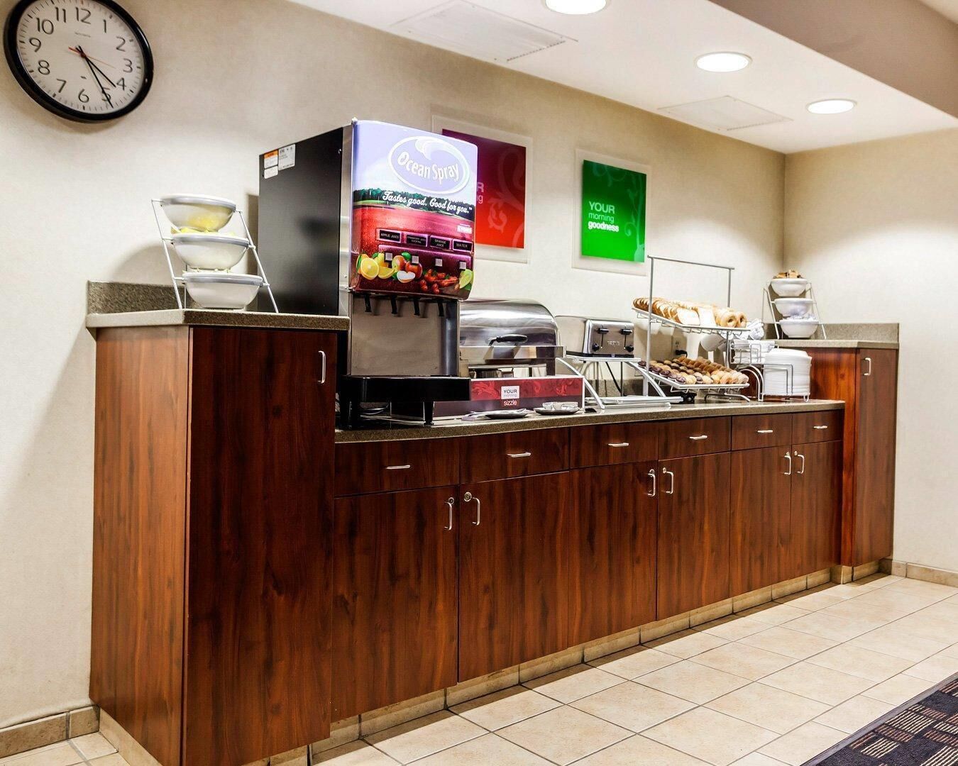 A hotel reception area with a coffee machine, a clock, and a sign that says "YOUR MORNING GOODNESS".
