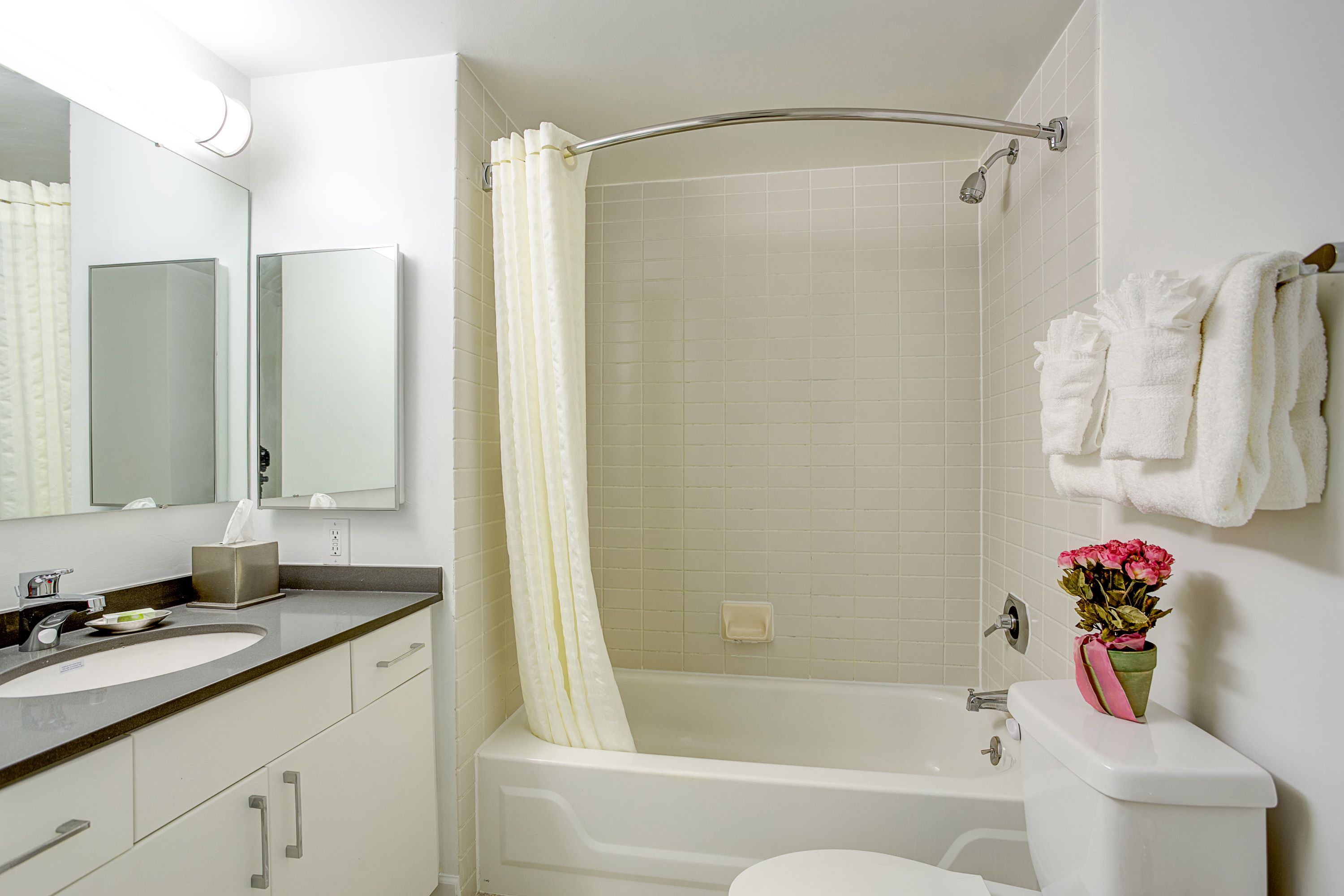 Un baño con lavamanos, espejo y bañera blancos.