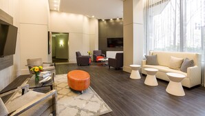 A modern living room with a sofa, chairs, a coffee table, and a TV. - Oakwood Crystal City (Arlington)