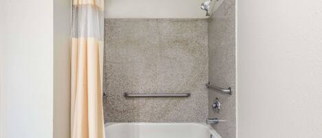 Une salle de bain standard équipée d’une baignoire, d’un rideau de douche et d’une barre d’appui.