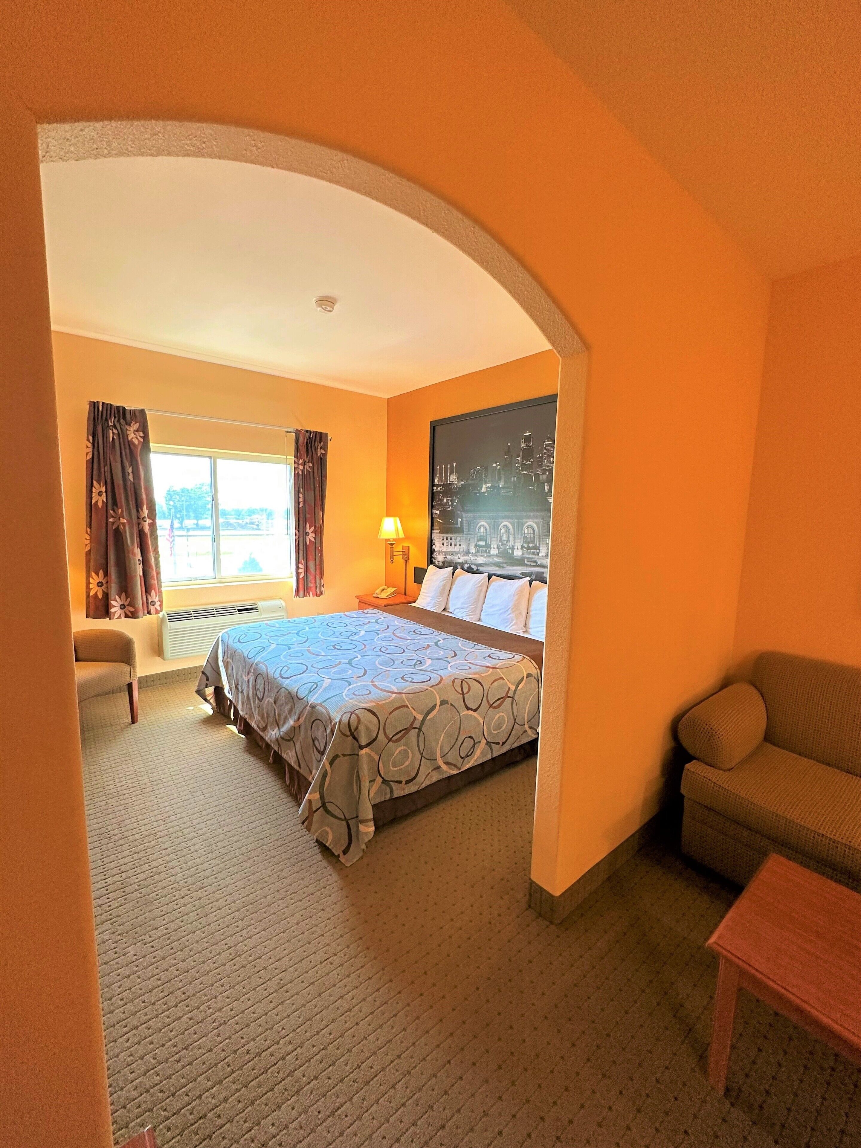 Una habitación de hotel con una cama, un sofá, un escritorio y un ventanal grande.