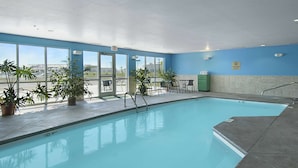 A swimming pool with clear blue water, surrounded by potted plants and outdoor seating. - Super 8 by Wyndham Topeka at Forbes Landing (Topeka)