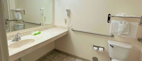 A bathroom with a sink, mirror, towel rack, toilet, and hand dryer.
