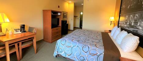 A hotel room with a bed, a desk, a television, and a wardrobe.