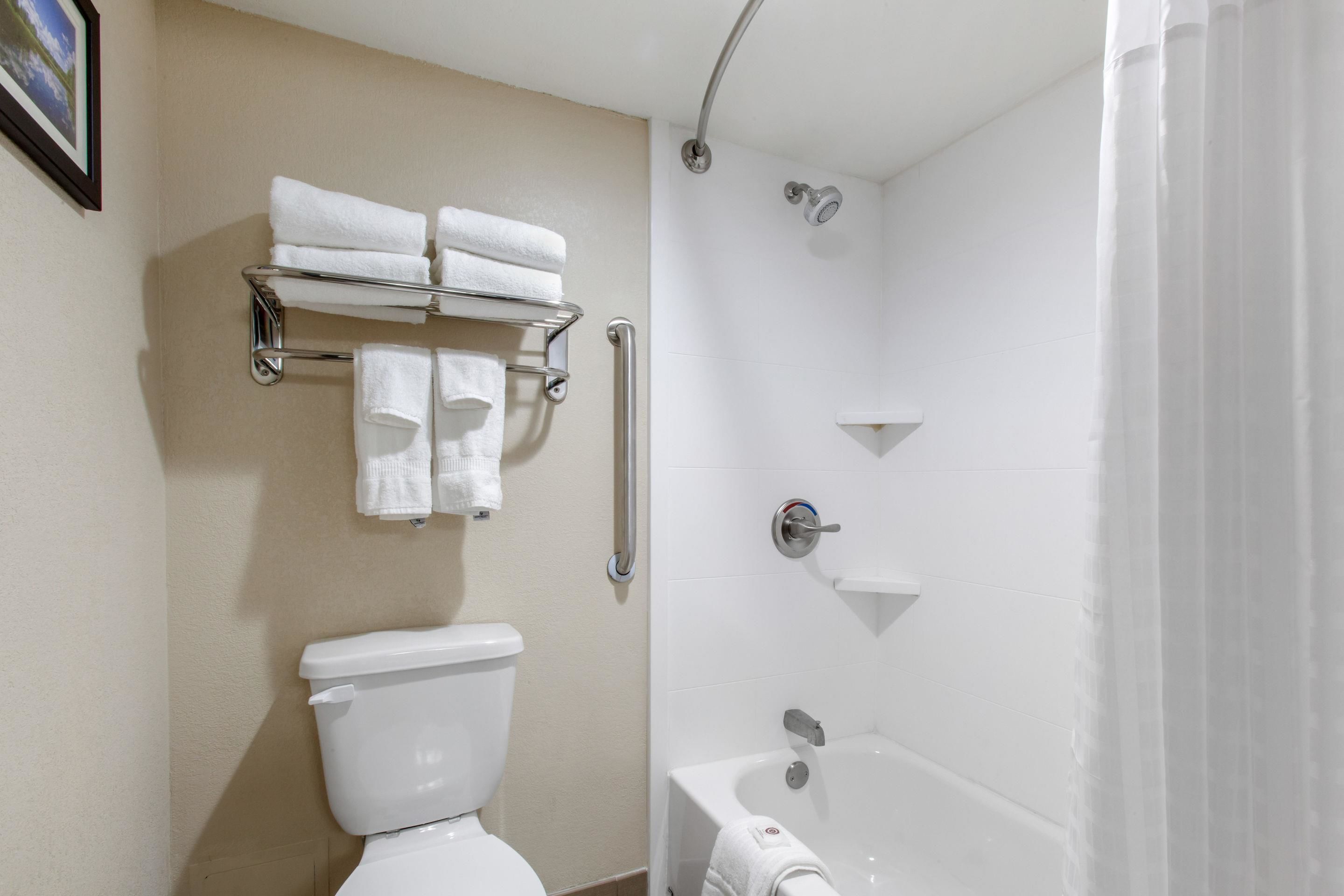 Un baño con inodoro, ducha y un perchero con varias toallas.
