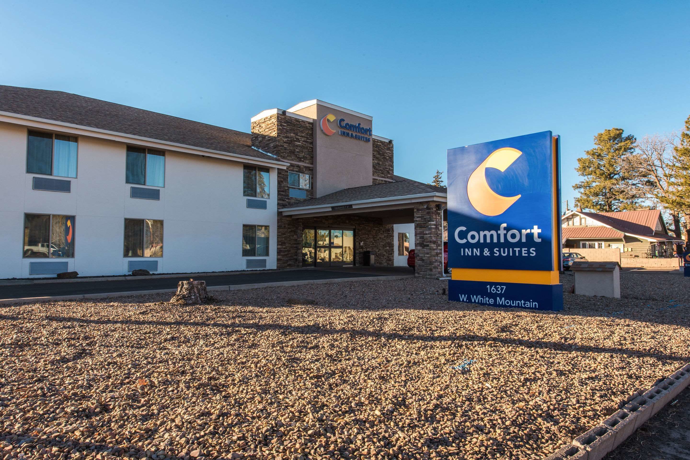 Un bâtiment de la chaîne Comfort Inn & Suites, avec une façade en pierre, une grande enseigne et une allée gravillonnée.