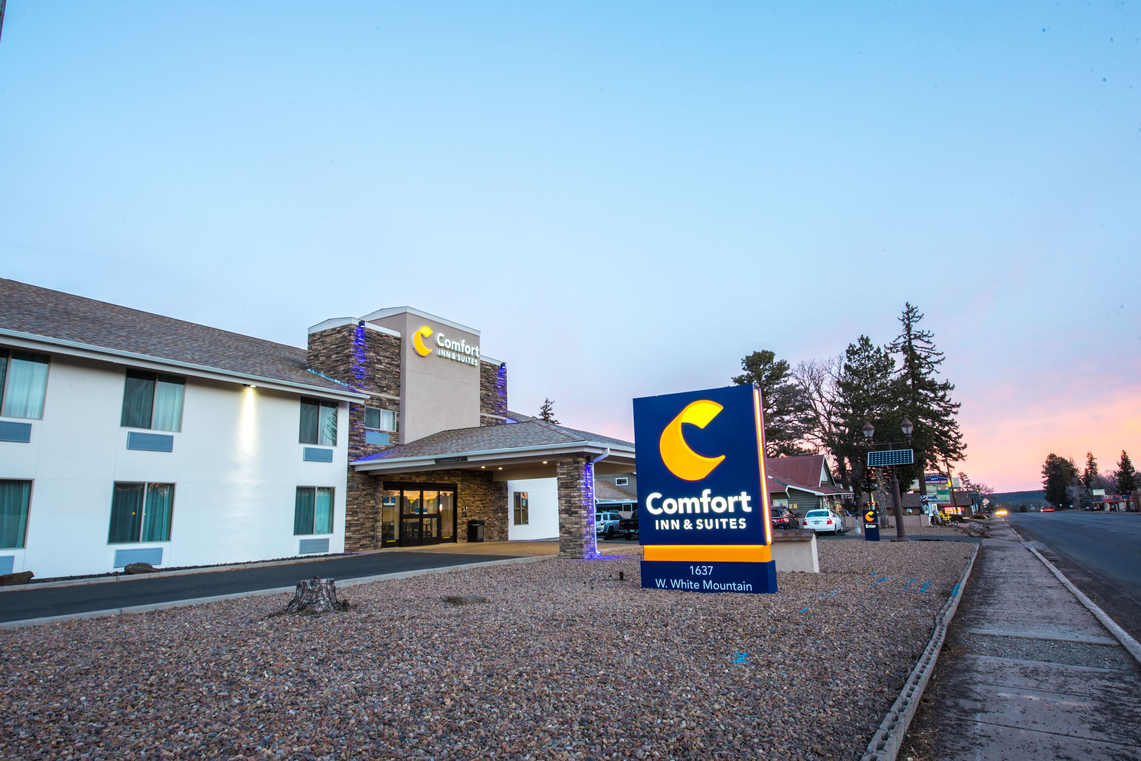 Señal de Comfort Inn & Suites, con un edificio moderno al fondo.