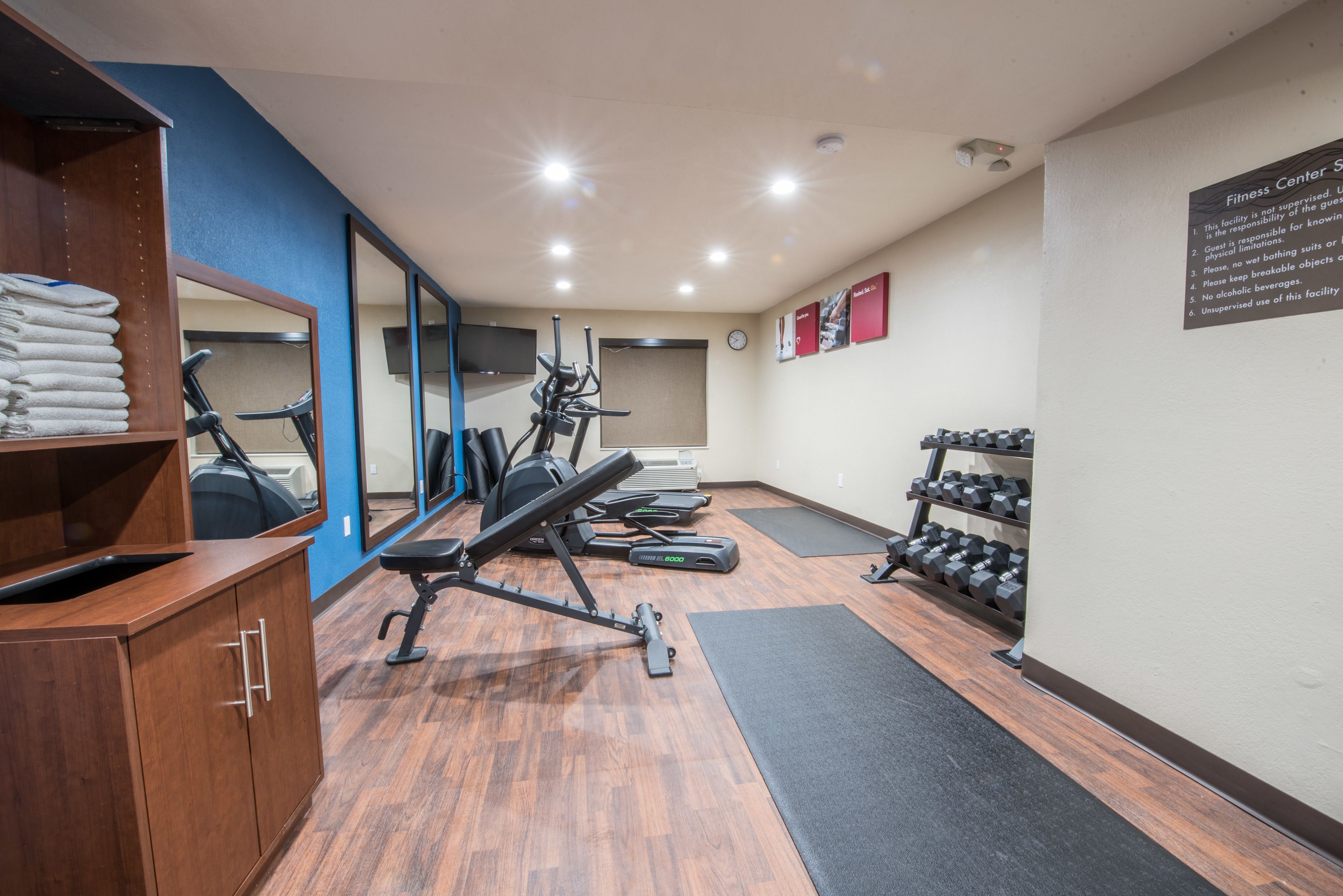 A fitness center with exercise equipment, a mirror, and a wall-mounted sign.