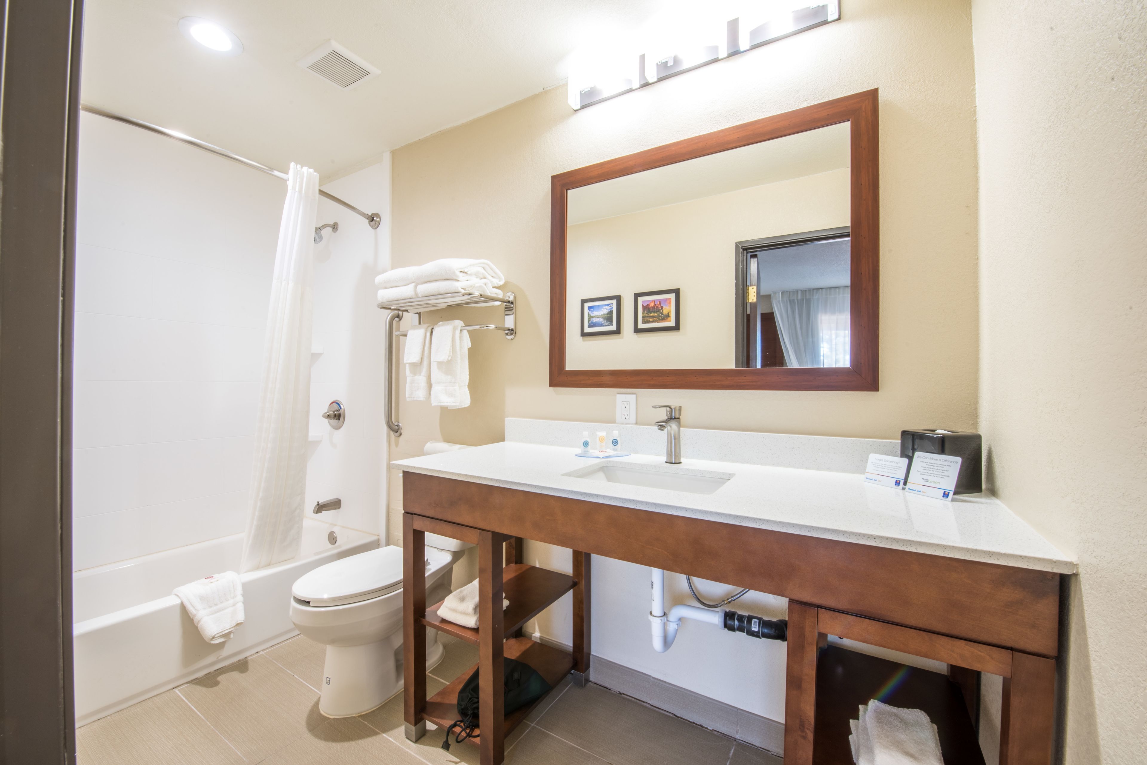 A bathroom with a white sink, mirror, and toilet. There are towels on the wall and a shower curtain.