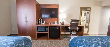 A hotel room with two beds, a desk with a computer, a microwave, a coffee maker, and a TV.