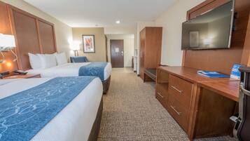 A hotel room with two beds, a desk, a TV, and a wardrobe.
