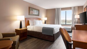 A hotel room with a bed, two bedside tables, a TV, a chair, and a window with curtains. - Wingate by Wyndham Bentonville AR (Bentonville)