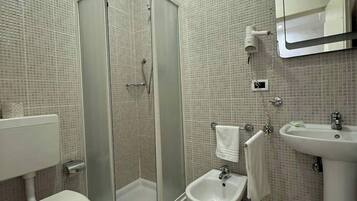 Ein modernes Badezimmer mit einer Duschkabine, Toilette, Bidet und Waschbecken.