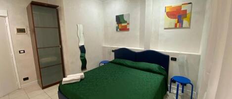 Ein Schlafzimmer mit Bett, Kleiderschrank, Spiegel und zwei Stühlen.