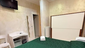 A hotel room with a large bed, a desk, a chair, a TV mounted on the wall, and a radiator. - Pollon Inn Sanremo (Sanremo)