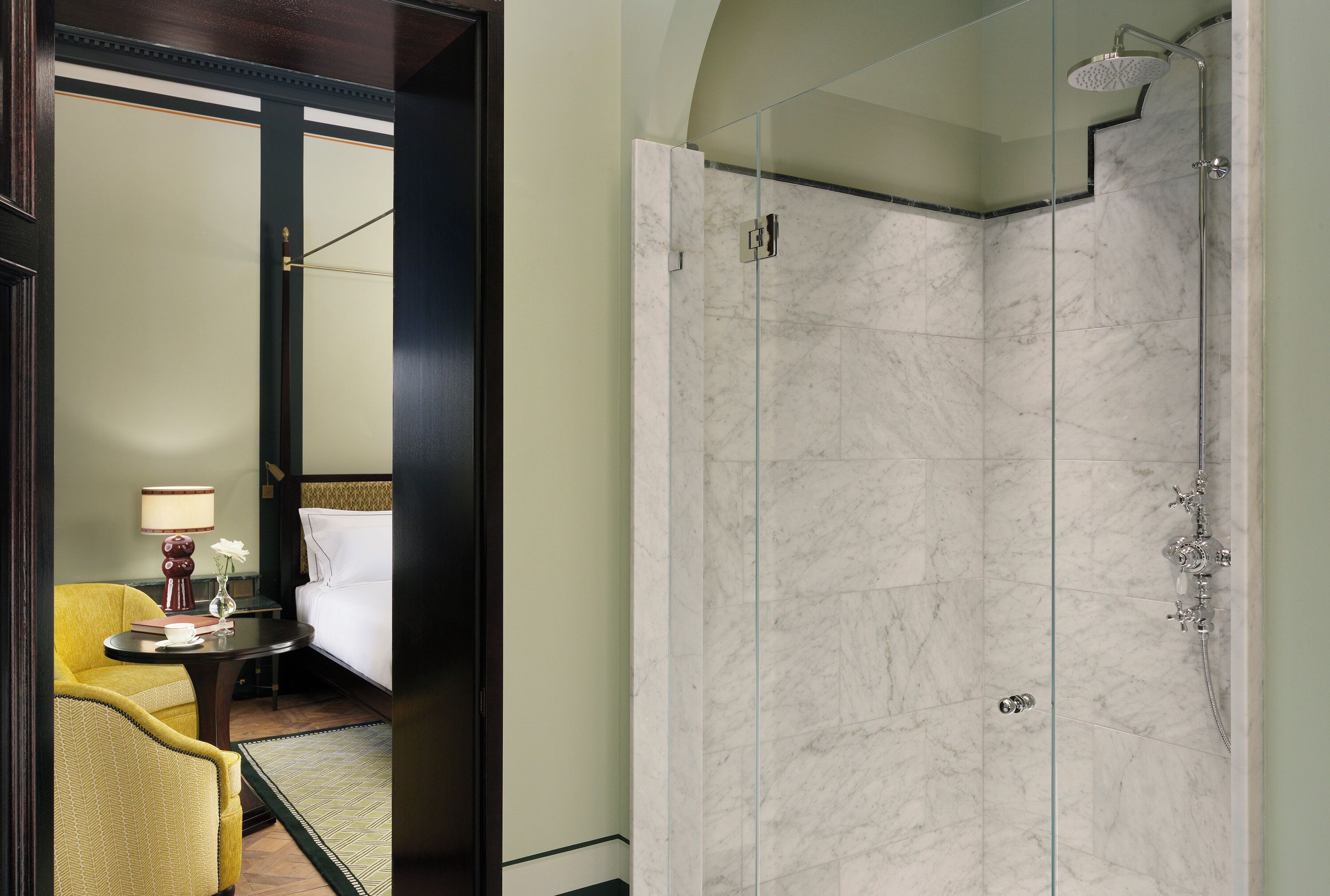 Une chambre d’hôtel avec une douche en marbre, un lit, une chaise et une petite table avec une lampe.