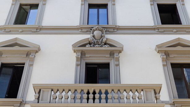 A building with a classical architectural style, featuring a central balcony with ornate balustrades and decorative columns.