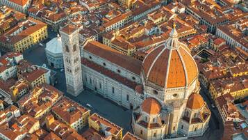 Vista aérea de una zona urbana densamente poblada con arquitectura histórica, incluyendo una catedral destacada con una cúpula grande y un campanario.
