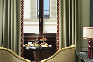 A dining area with a table set for breakfast, including croissants and fruit, and a vase with a flower. - Palazzo Ruspoli (Florence)