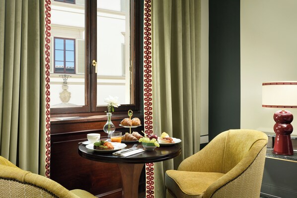 Une chambre d’hôtel avec une table à manger dressée pour le petit-déjeuner, comprenant des croissants, des œufs et des fruits.