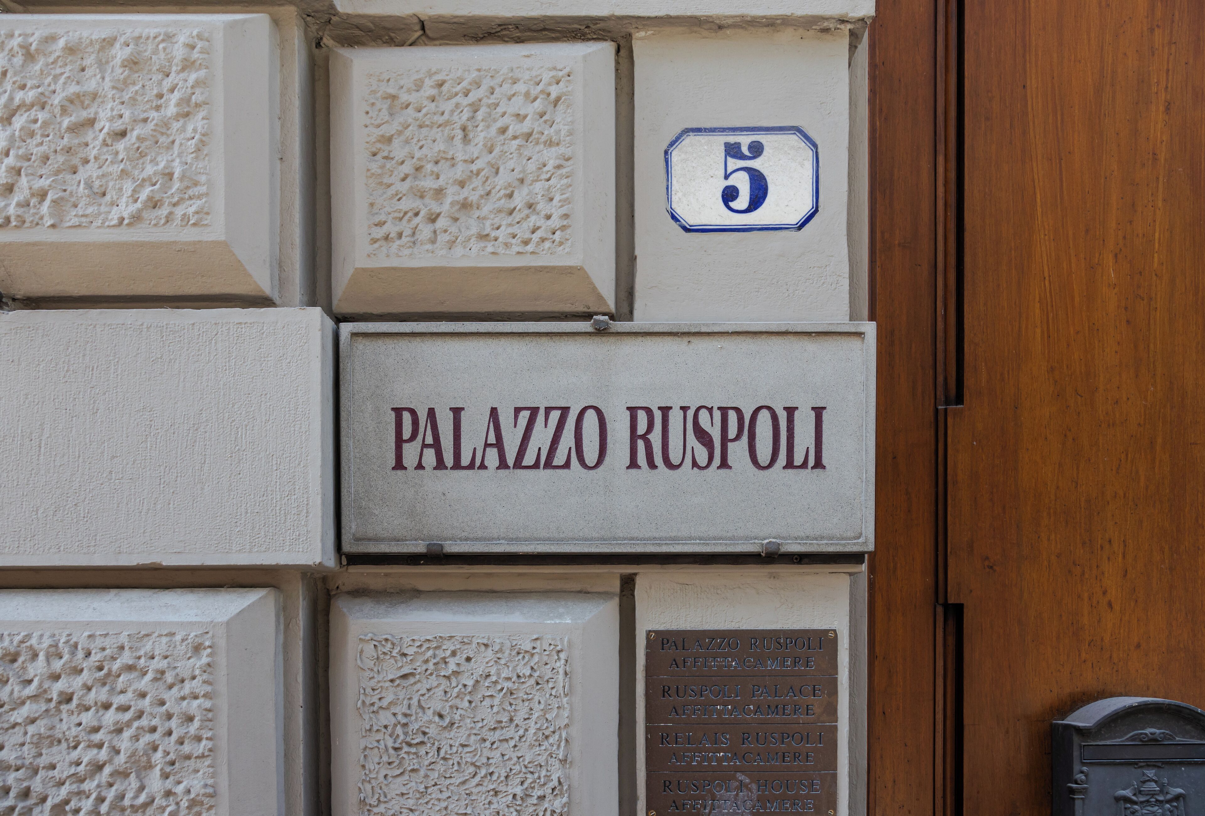 A wall with multiple plaques and a sign reading "PALAZZO RUSPOLI".