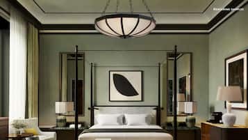 Una cama con dosel, un reposapiés a cuadros, un cuadro abstracto de gran tamaño y una lámpara colgante en una habitación de hotel.