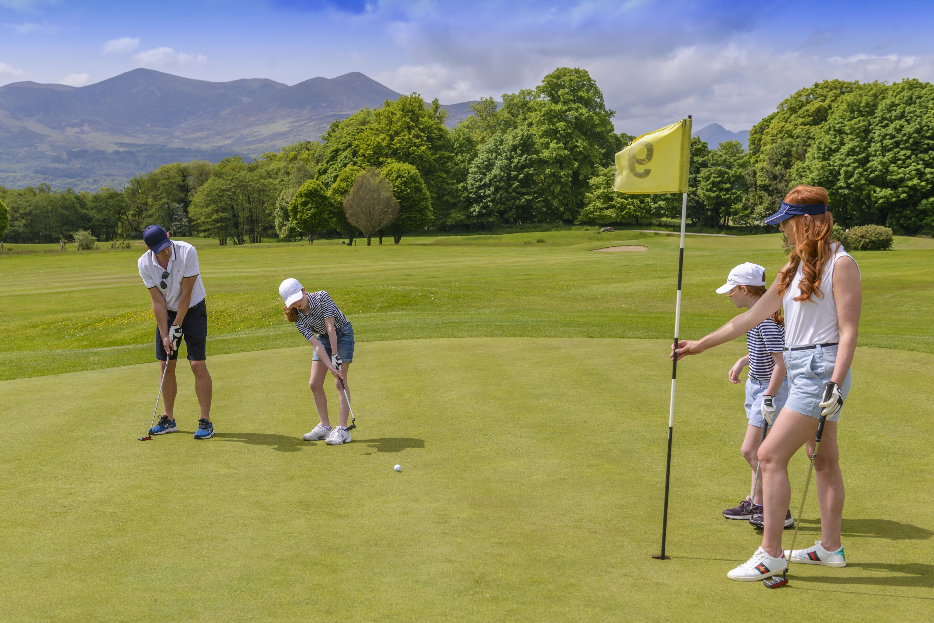 Un campo de golf con un mástil de bandera y un fondo montañoso.
