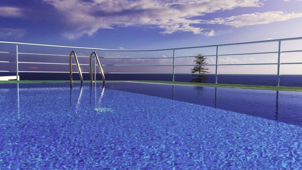 A swimming pool with clear blue water, metal railings, and a view of the ocean.