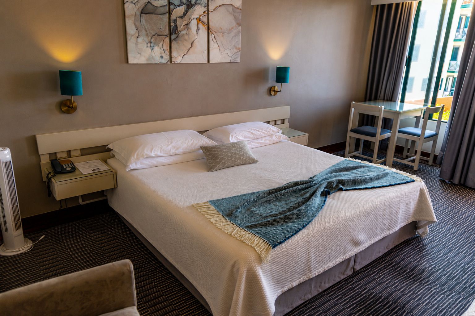 Een hotelkamer met een groot bed, nachtkastjes, een bureau en stoelen.