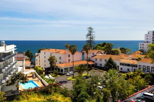 Ein Küstenhotel mit mehreren Gebäuden, einem Schwimmbecken und Blick aufs Meer.