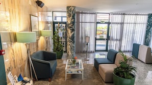 A modern lobby with a marble wall, a coffee table, sofas, and potted plants.