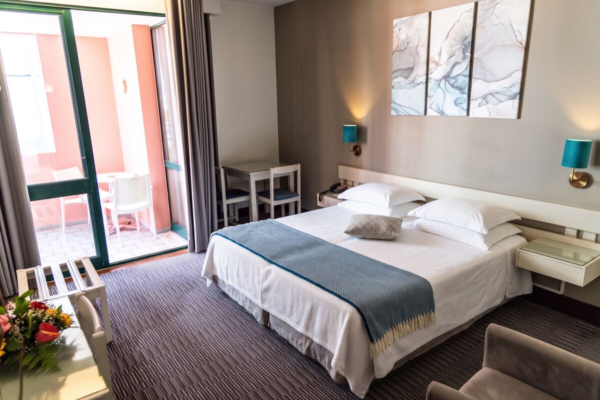 A hotel room with a bed, bedside tables, a desk, and a chair.