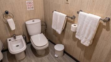 Un baño con bidé, inodoro y lavamanos.