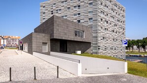 A modern building with a unique facade, a parking sign, and a river in the background.