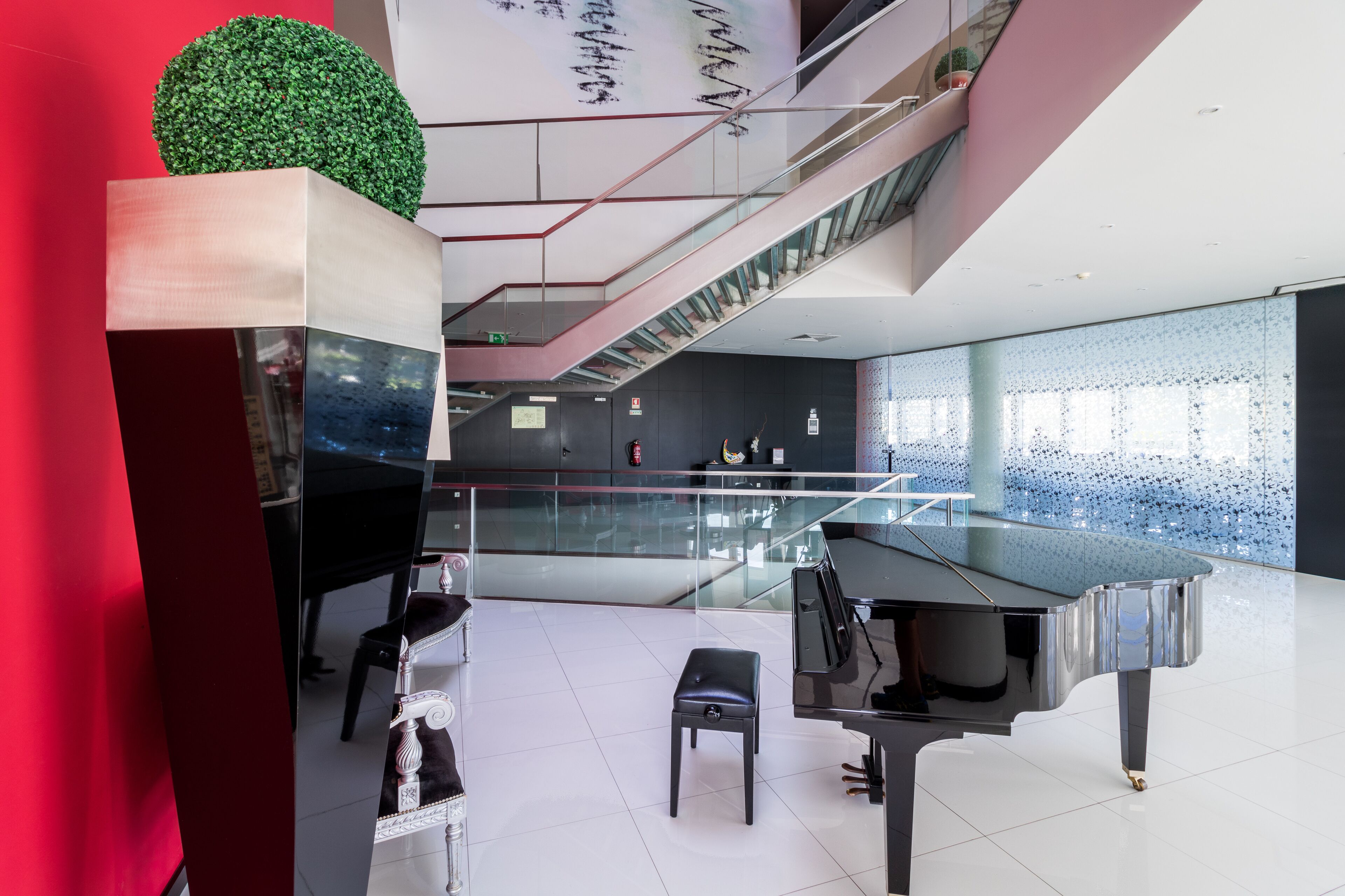 A modern interior with a grand piano, a glass staircase, and a decorative green sphere.