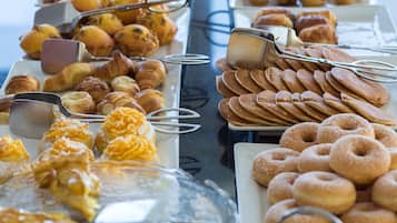Ein Buffet mit verschiedenen Backwaren und Gebäck, darunter Croissants, Muffins und Donuts.