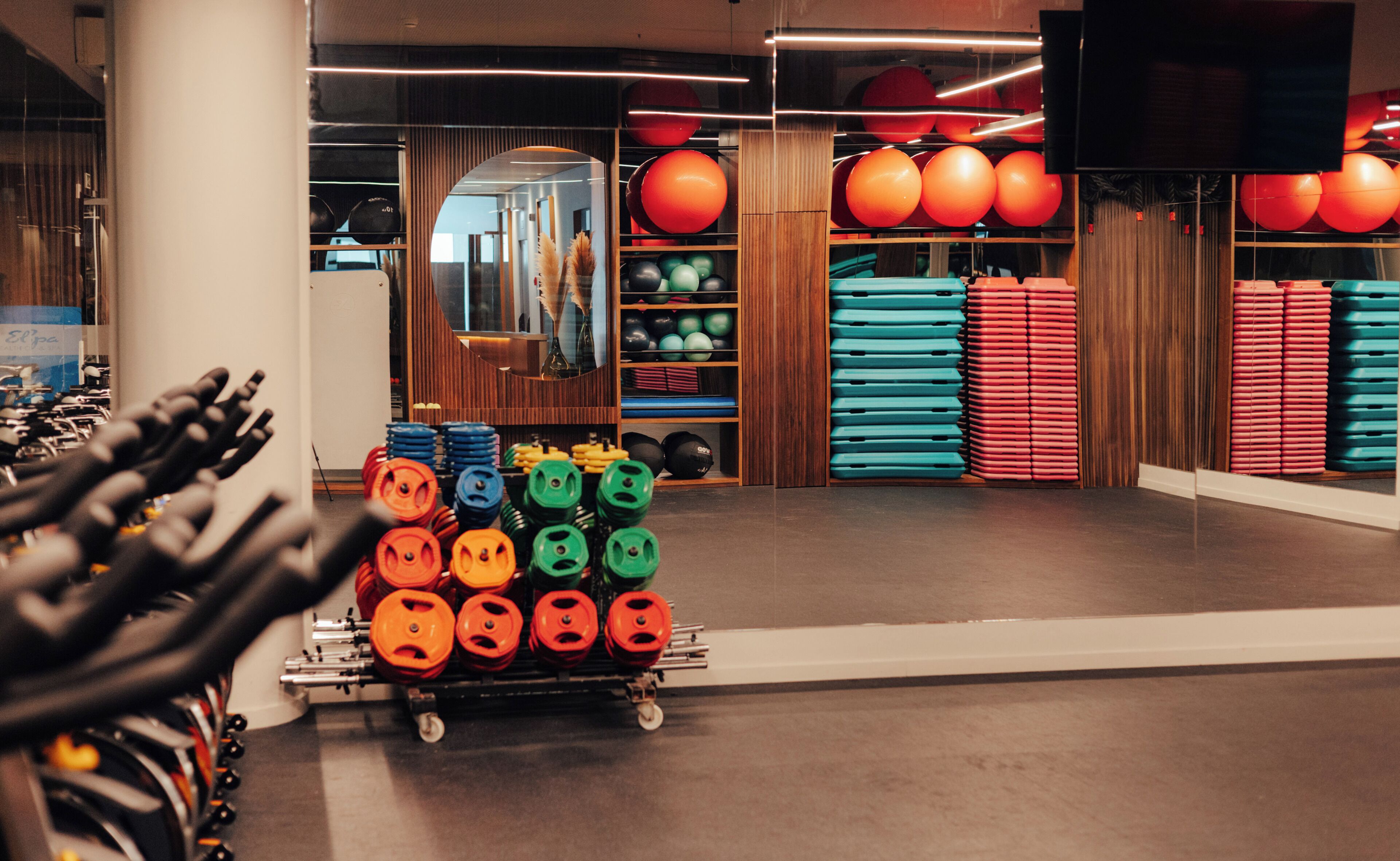 A gym with weightlifting equipment, exercise balls, and mats.
