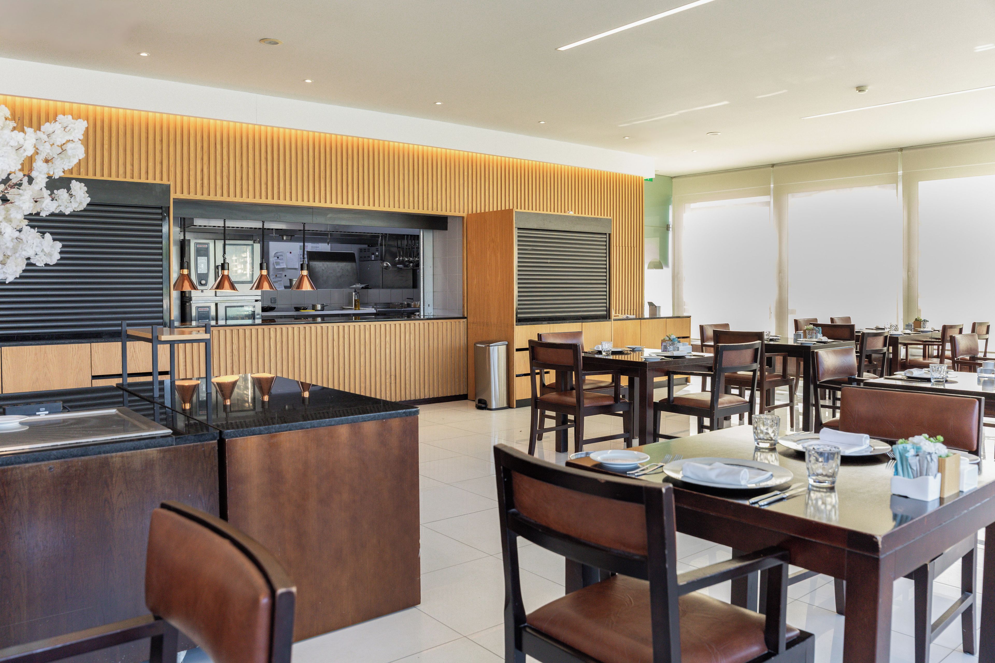 En moderne restaurant med en central ø, træpaneler og et køkkenområde.