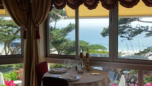 A table set with a view of the ocean through large windows, curtains, and a table lamp. - TI AL LANNEC Hotel - Restaurant & Spa (Trébeurden)