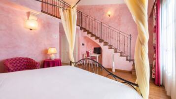 Un dormitorio con cama, escritorio, silla, escalera y ventana con cortinas.