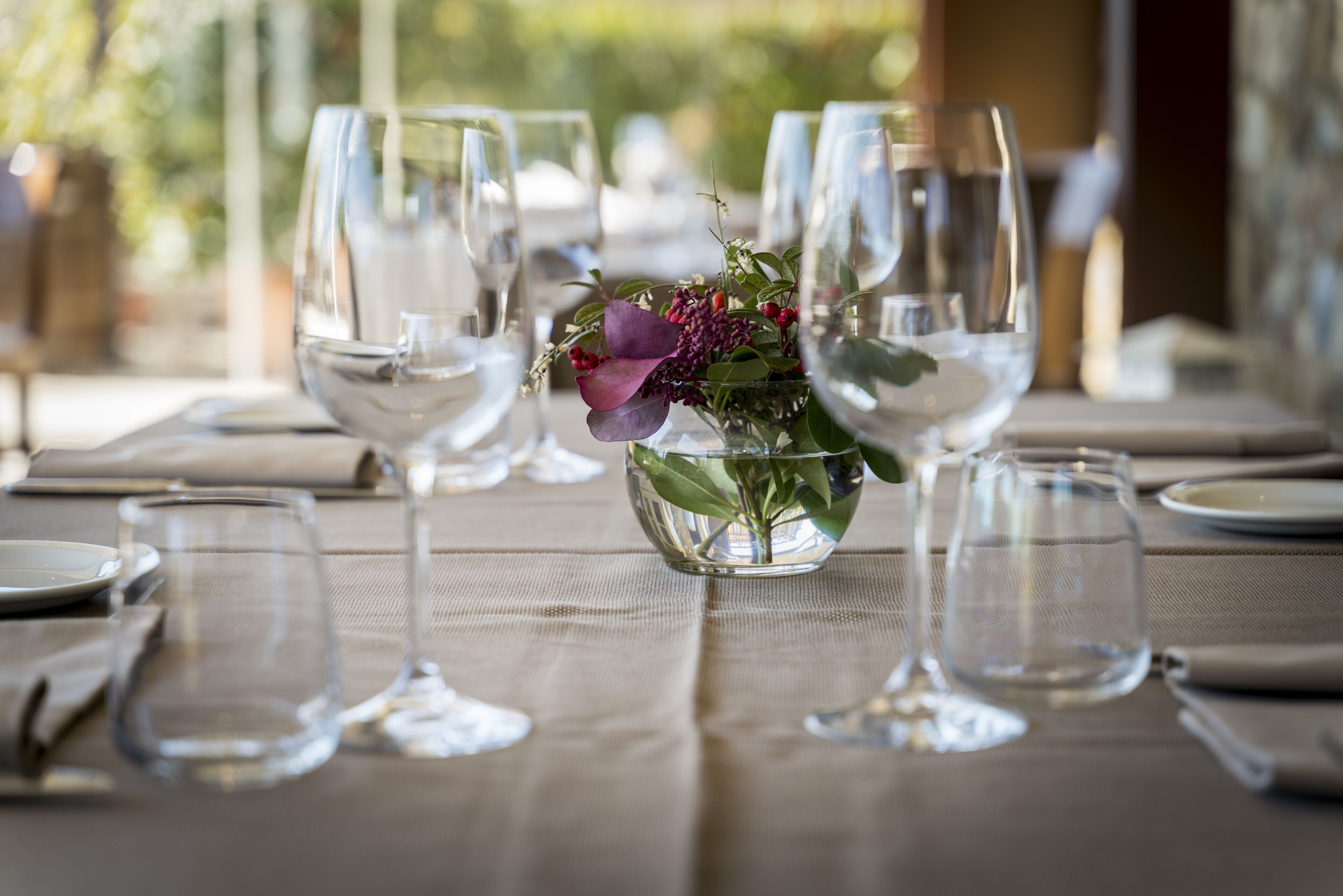 A dining table set with empty wine glasses and a centerpiece of flowers.