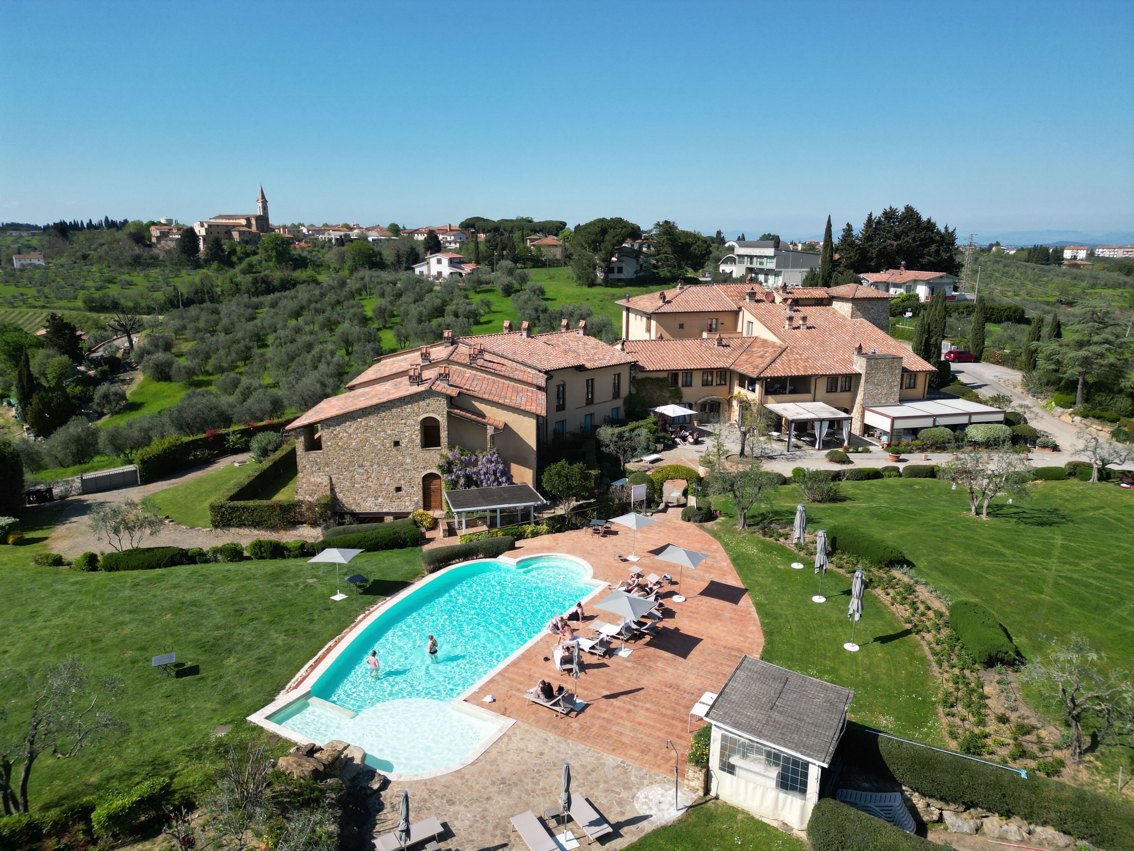 Una amplia villa con piscina, varias zonas de estar al aire libre y un jardín bien cuidado.