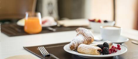 Una mesa con un croissant, bayas y un vaso de jugo de naranja para el desayuno.