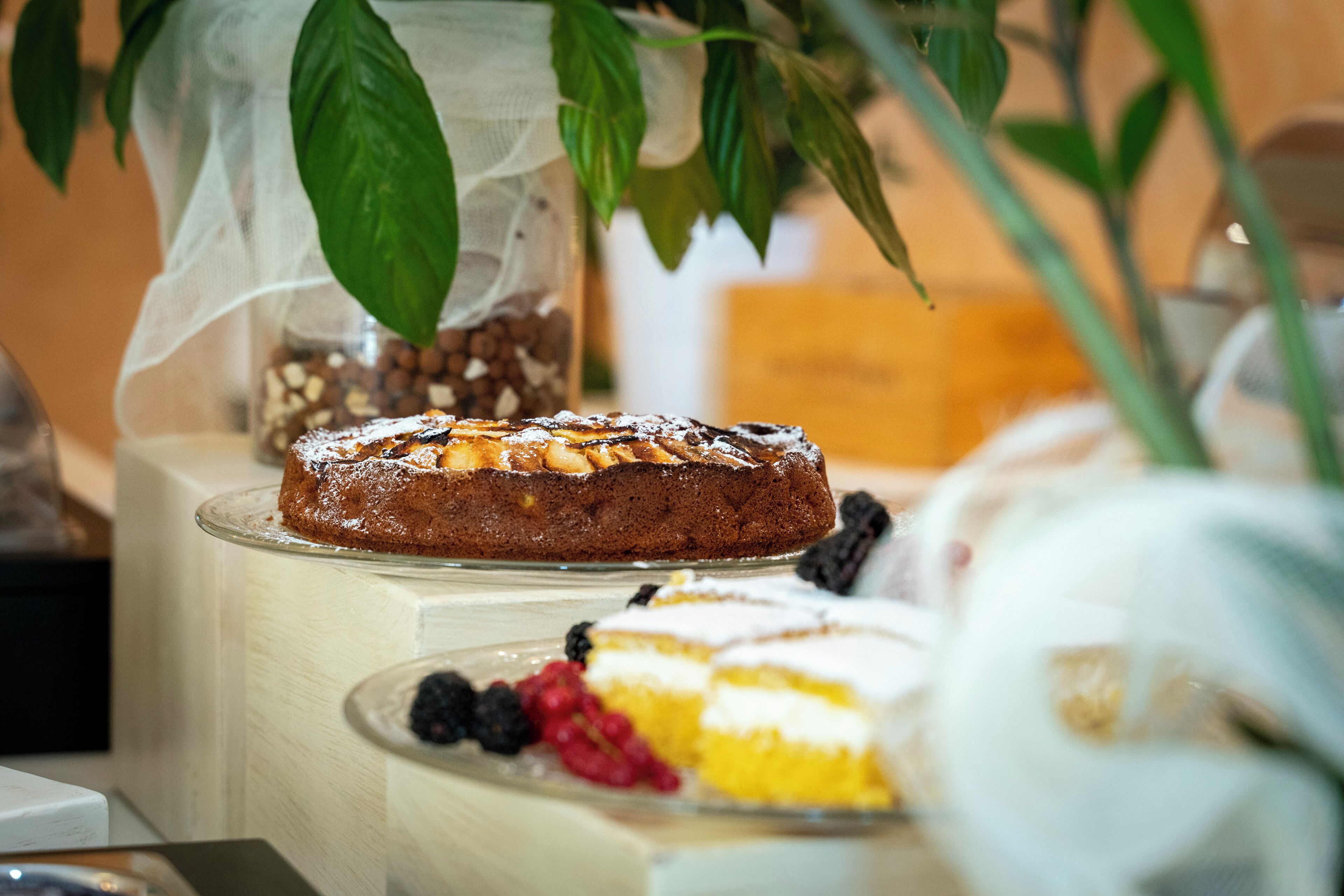A dessert display with cakes and berries on a wooden table.