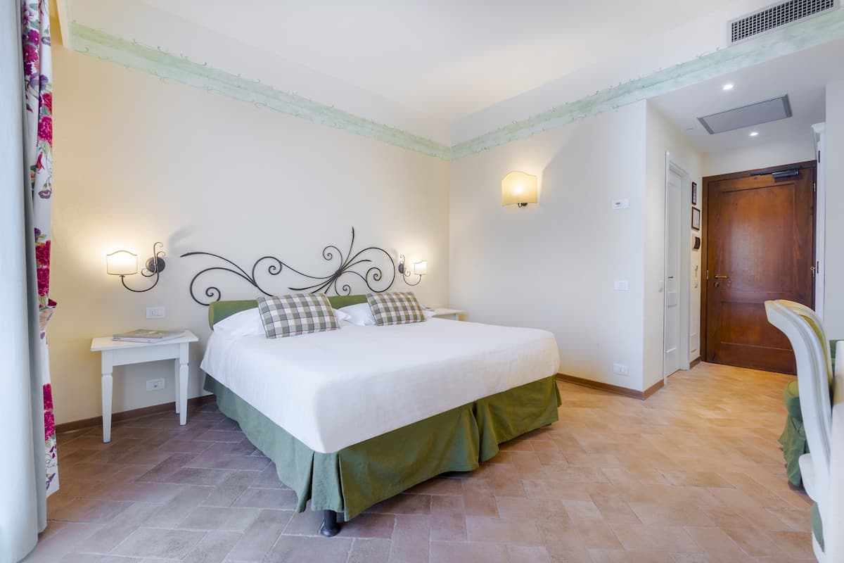 A bedroom with a bed, nightstands, a wall-mounted light, and a door.