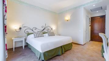 Una camera da letto con un letto, comodini, una lampada a parete e una porta.