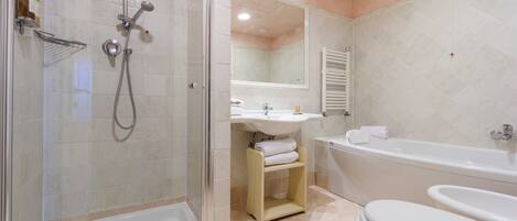 A modern bathroom with a glass-enclosed shower, a sink, a bathtub, and a toilet.