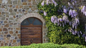 A stone building with a wooden door and an arched window. - Hotel Borgo di Cortefreda Relais (Barberino Tavarnelle)