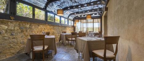 A restaurant with stone walls, wooden tables, and hanging lights.