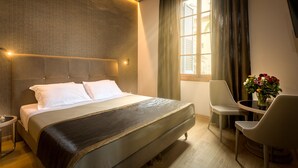 A hotel room with a large bed, a bedside table, a chair, and a window with curtains. - Tourist House Liberty (Florence)